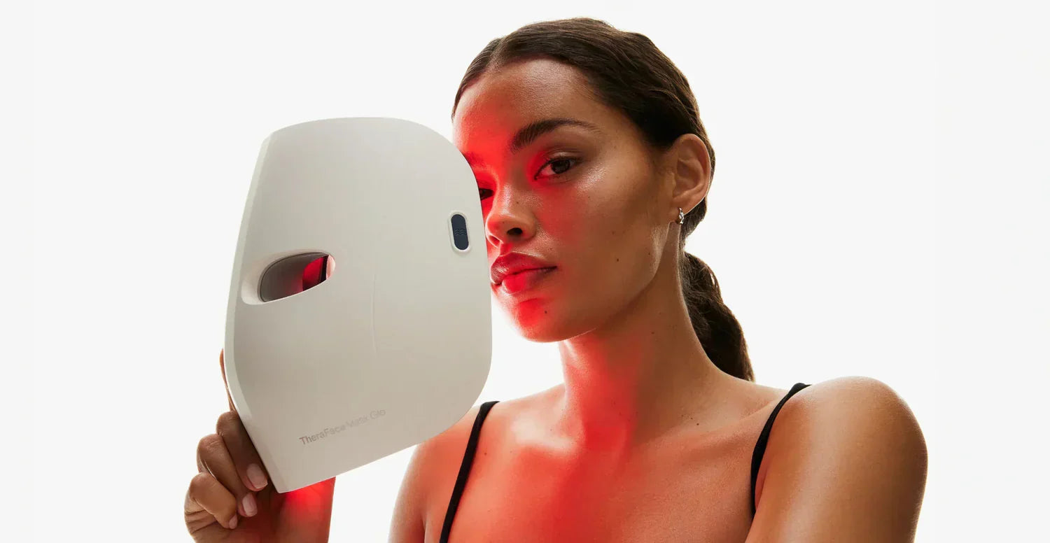 Woman using a theraface mask glo skincare device emitting red light on her face