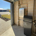 AquaCo water softening filter system installed in a garage with connected copper pipes and outdoor view
