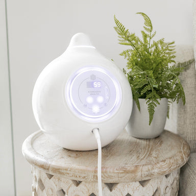 HYDROGEN HEALTH white hydrogen breathing system with digital display on wooden table next to green plant