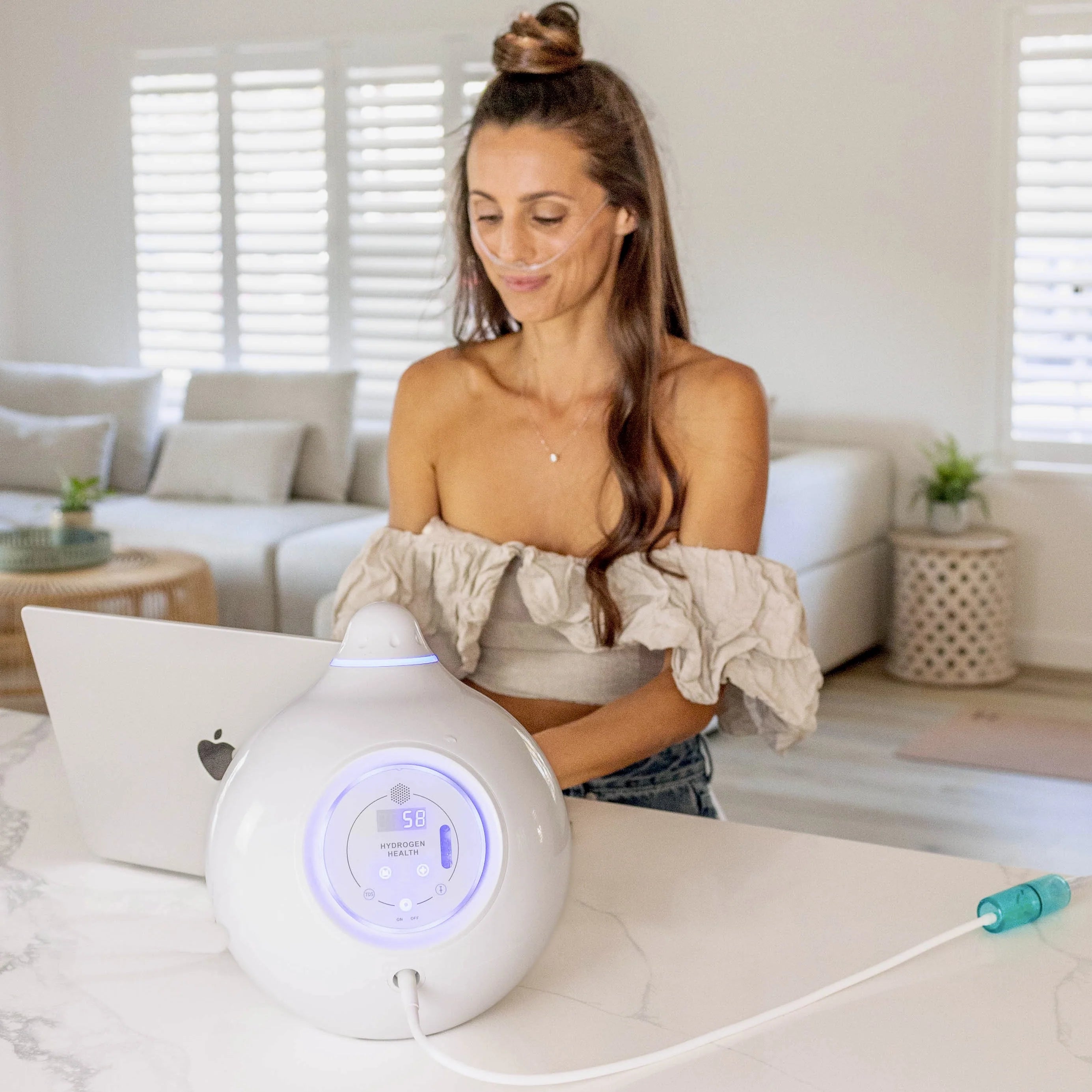 HYDROGEN HEALTH hydrogen breathing system with woman using it at home near laptop