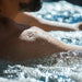 Person relaxing in a Nuvie ice bath with water droplets on shoulder and bubbling cold water