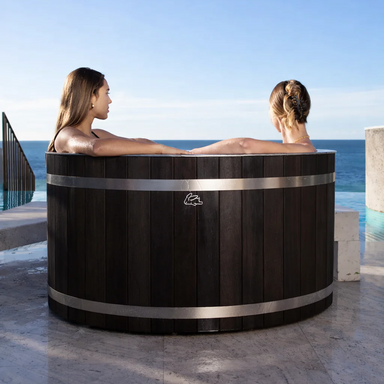 Chill Bunny dark wooden ice bath with two women relaxing outdoors by the ocean
