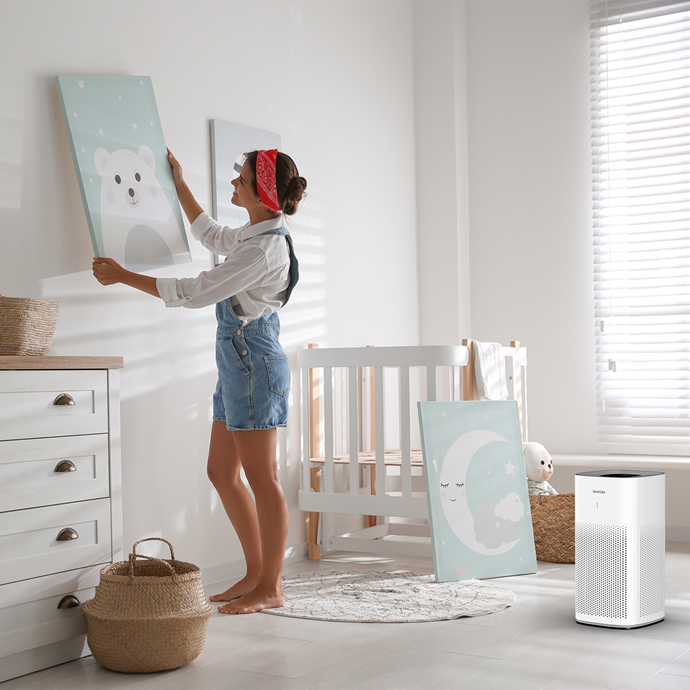 Ionmax air purifier in a bright nursery with a woman hanging polar bear wall art