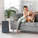 Ionmax dehumidifier in modern living room with woman sitting on gray sofa petting a dog