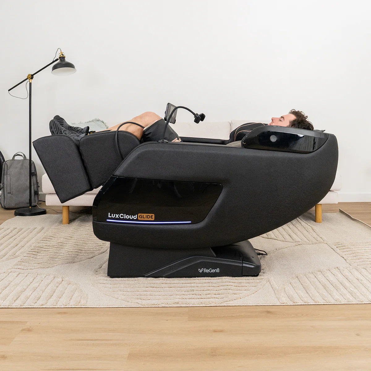 Lifespan Fitness LuxCloud Glide massage chair in black with reclined person using it in modern living room