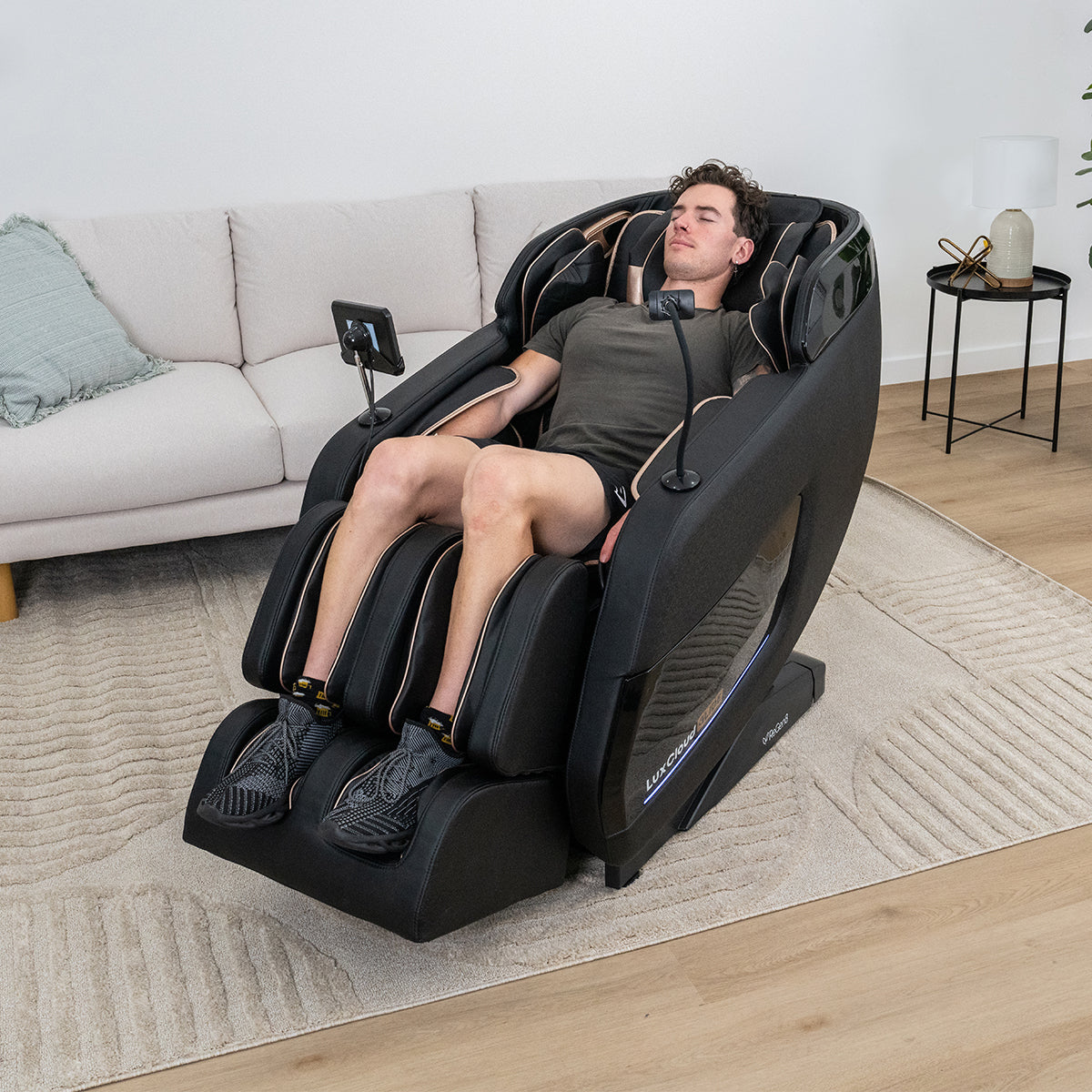 Lifespan Fitness black massage chair with man relaxing in modern living room setting