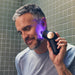 Man using Therabody theraface pro skincare device with glowing blue light on face