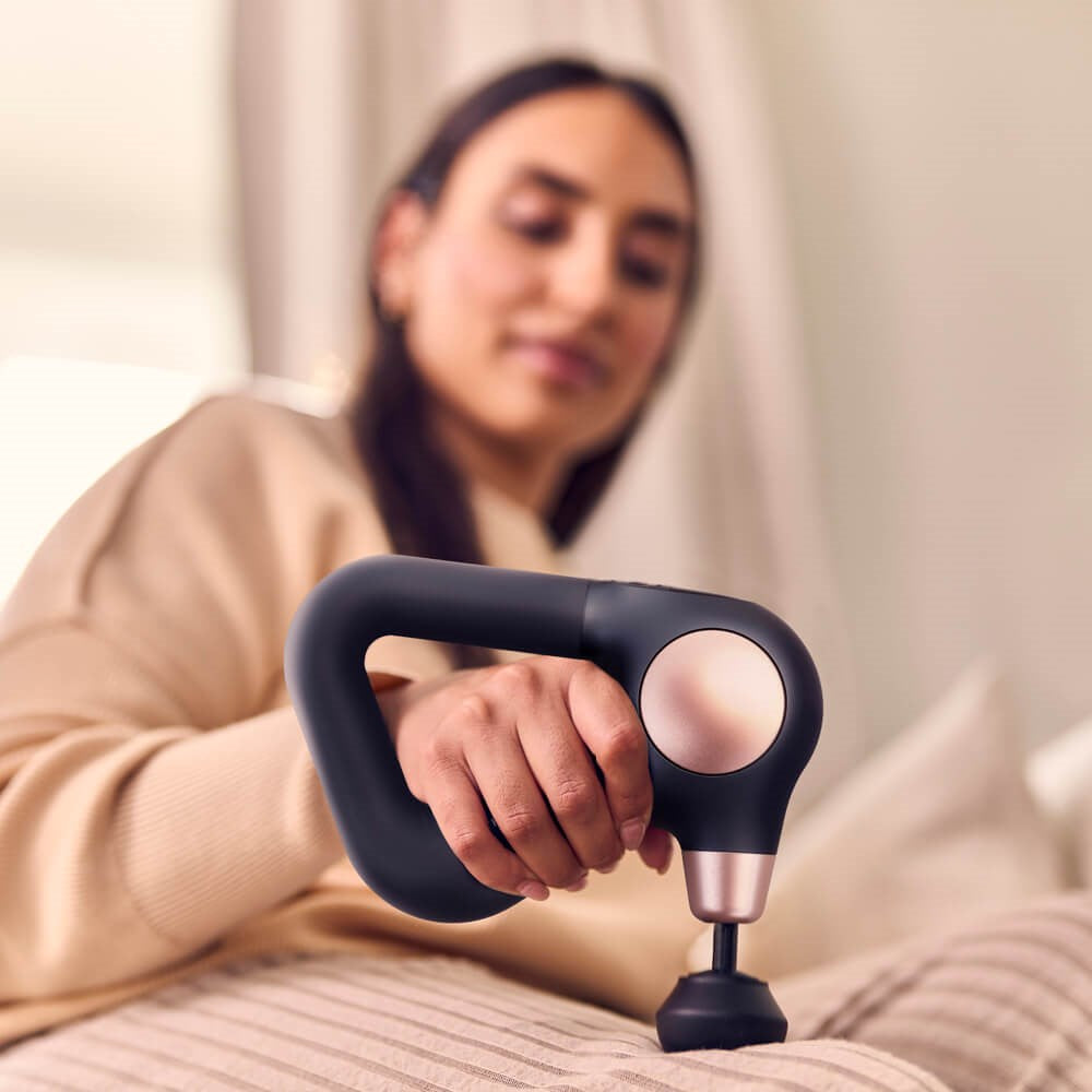 Therabody massage gun in black and rose gold held by woman for muscle relief