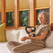 Therabody massage gun used by woman for arm muscle relief on beige couch at home