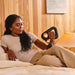 Therabody massage gun in black used by woman relaxing on bed for muscle relief