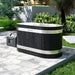 Nuvie black wood finish outdoor ice bath with stainless steel bands on a stone patio surrounded by greenery