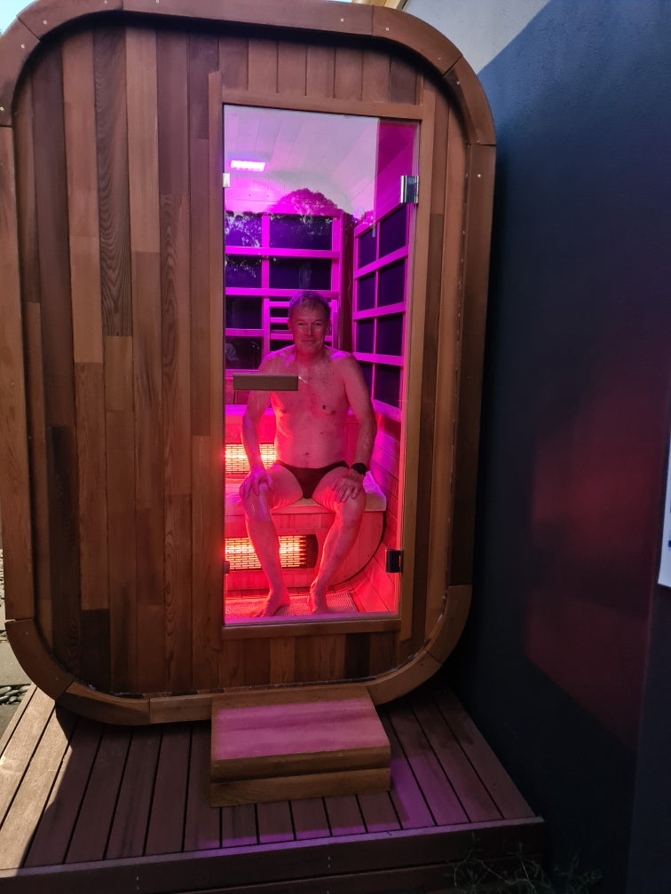 Stryke Recovery outdoor infrared sauna with wooden exterior and red light therapy interior