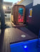 Stryke Recovery outdoor infrared sauna with wooden exterior and glass door next to a pool at dusk