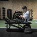 Man using Lifespan Fitness compression boots while sitting on a bench in a gym setting