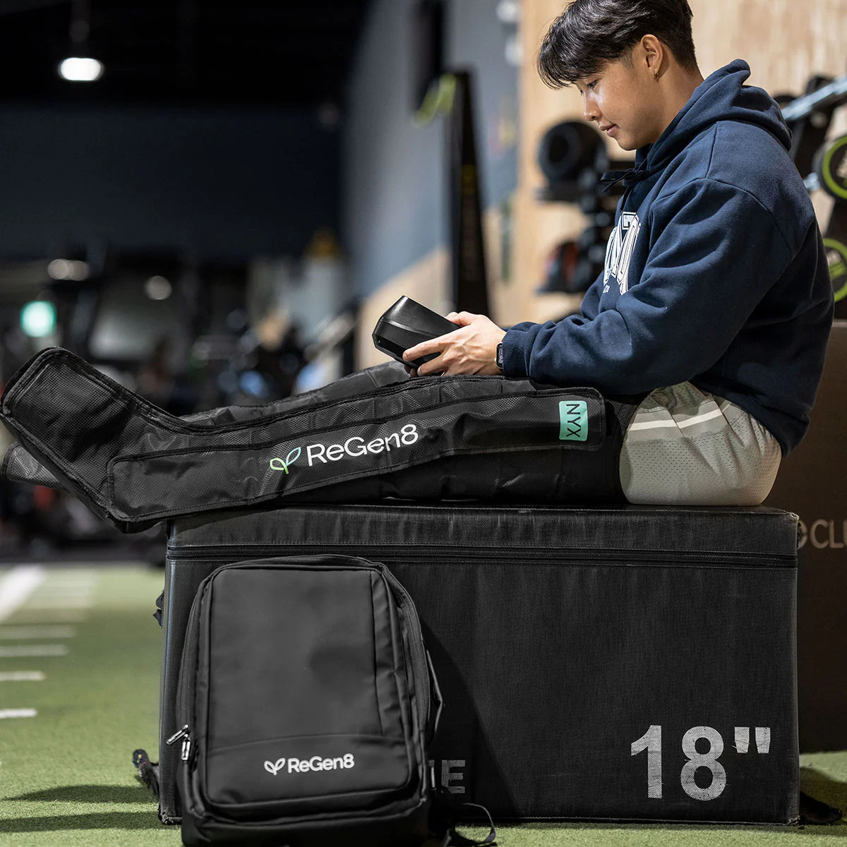 Lifespan Fitness ReGen8 compression boots on man sitting on workout box using control device