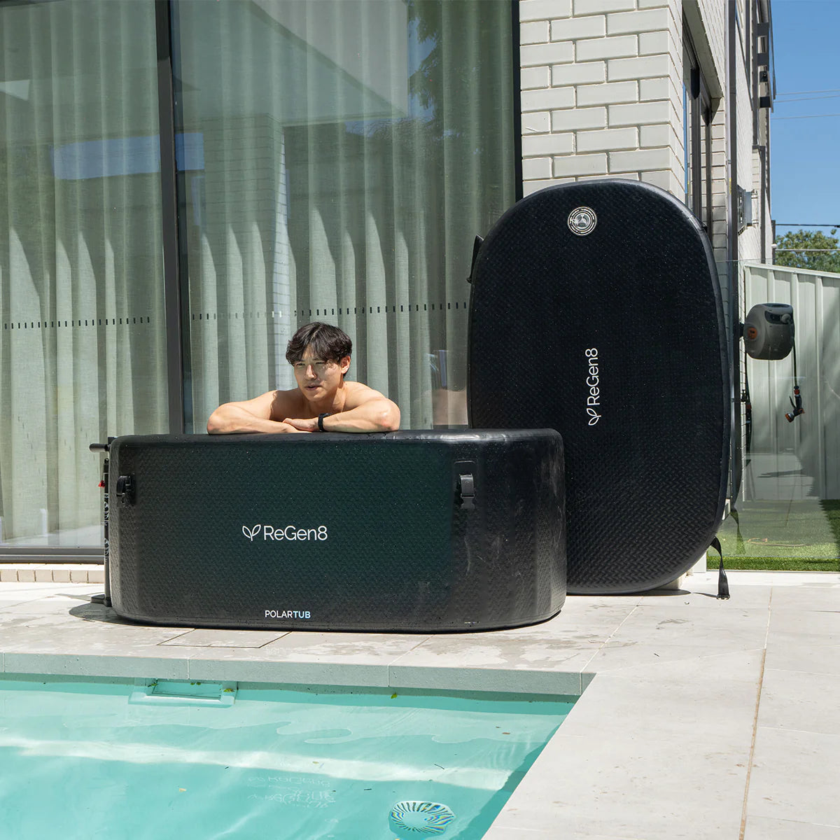 Lifespan Fitness black ReGen8 ice bath near pool with man relaxing inside on a sunny day
