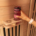 Hand placing pink water bottle on wooden holder inside Lifespan Fitness sauna with light wood paneling