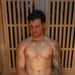 Man relaxing inside a Lifespan Fitness sauna with wooden slat walls and visible sweat on chest