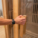 Person opening Lifespan Fitness wooden sauna door with glass panel and wooden handle