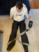 Person using Stryke Recovery black compression boots connected to control device for leg therapy