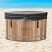 Stryke Recovery wooden ice bath with black cover on sandy beach near ocean