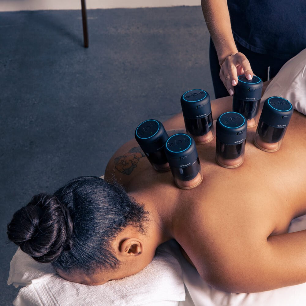 Therabody hot and cold therapy cupping device set applied on womans back during treatment session