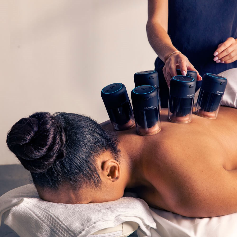 Therabody hot and cold therapy cupping device applied on a woman's back during a massage session