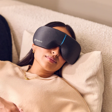 Therabody eye and temple massager worn by woman relaxing on couch with eyes covered