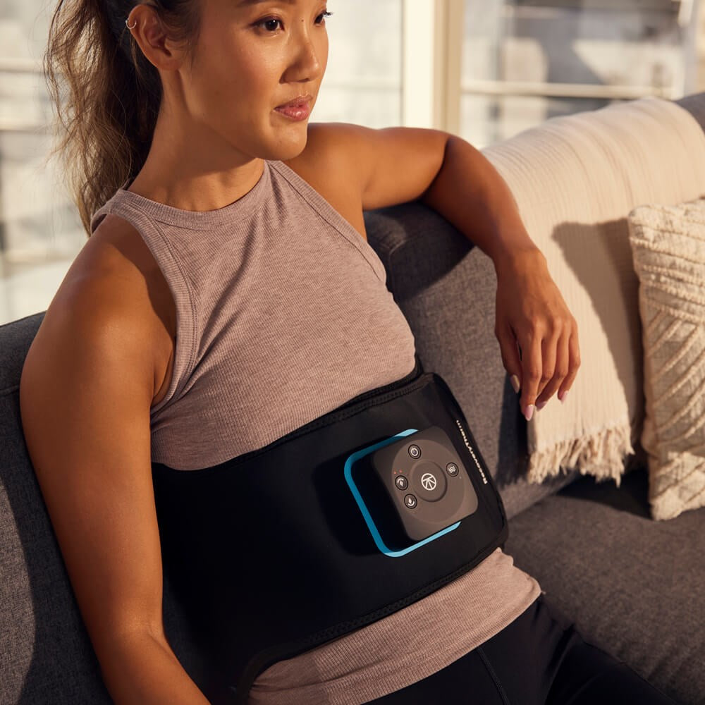 woman wearing therabody recoverytherm back on a couch
